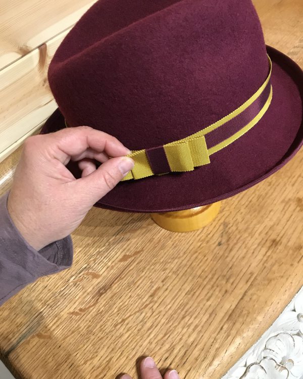 Susan putting the finishing touches to a burgundy felt hat